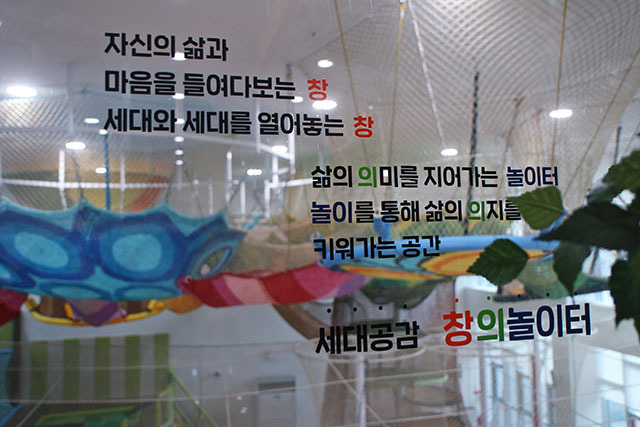 <strong>그물놀이터가 내려다보이는 유리창에 세대공감창의놀이터가 지향하는 표어가 있다.</strong>