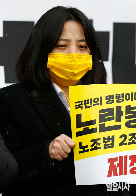 류호정 의원이 추위에 떨며 한 손가락으로 손피켓을 잡고 있다.