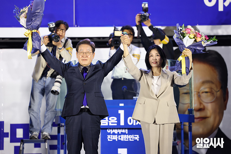 이재명 대통령과 배우자 이혜경 여사가 4일 오전, 서울 여의도 국회에 마련된 연단 위에서 당선 축하 꽃다발을 들어보이고 있다. ⓒ문경덕 기자