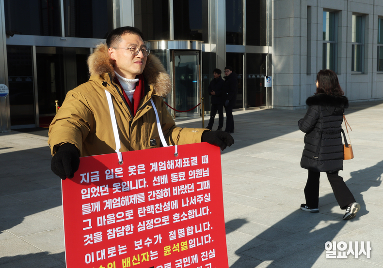김상욱 국민의힘 의원이 지난해 12월14일, 윤석열 전 대통령의 탄핵소추 2차 표결을 앞두고 서울 여의도 국회 앞에서 찬성을 호소하는 팻말을 목에 걸고 호소하고 있다. ⓒ고성준 기자