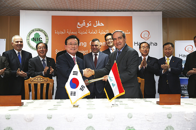 한화건설 이근포 대표이사(악수하는 좌측)와 사미 알 아라지(Dr.Sami Al Araji) 이라크 NIC 의장이 한화건설 관계자와 이라크 정부인사들이 참석한 가운데, 한화건설의 21.2억불(한화 약 2조3400억원) 규모 이라크 비스마야 신도시 사회기반시설공사 수주를 위한 서명을 하고 악수를 하고 있다.