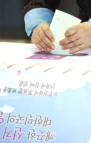 10·28재보선에서 한 유권자가 투표함에 투표용지를 넣고 있다.