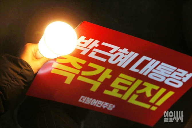 한 시민이 촛불집회 도중 '박근혜 대통령 즉각 퇴진'이라는 글귀가 적힌 피켓을 들고 있다. <사진=사진공동취재단>