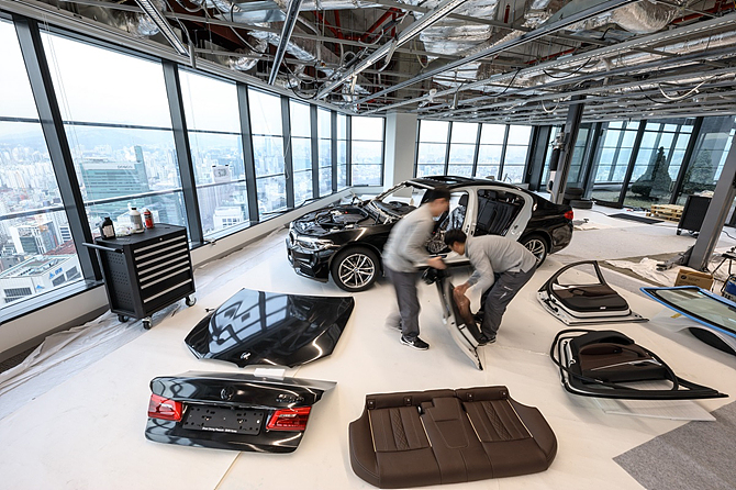 BMW 5시리즈 출시행사 도중 엔지니어들이 분해된 차량을 조립하고 있다.