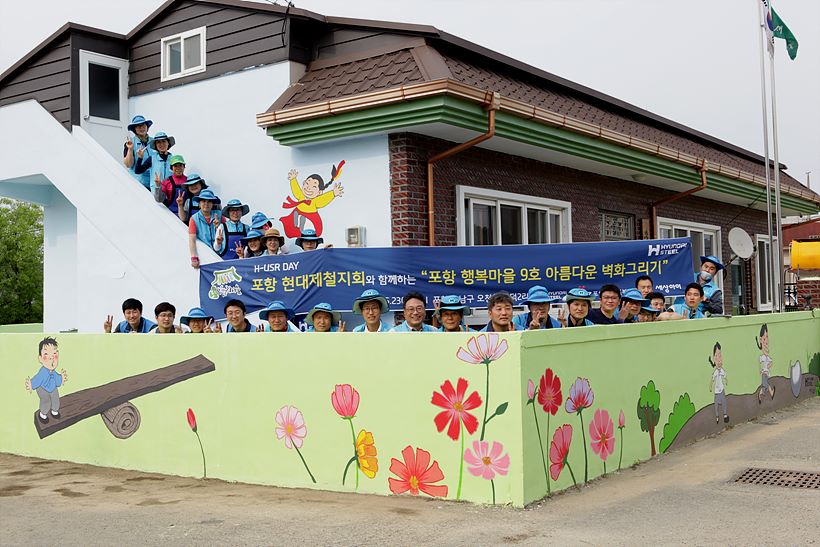 지난 23일 봉사활동에 참가한 봉사자들이 자신들이 그린 벽화 앞에서 기념촬영에 임하고 있다. <사진=현대제철 제공>