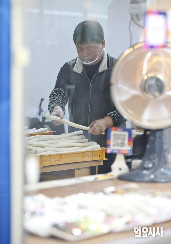 설을 앞두고 있는 18일 오전 서울 마포구 창전동에서 떡집을 운영하는 김시호씨가 기계가 뽑아낸 가래떡을 건조시키기 위해 정리하고 있다.